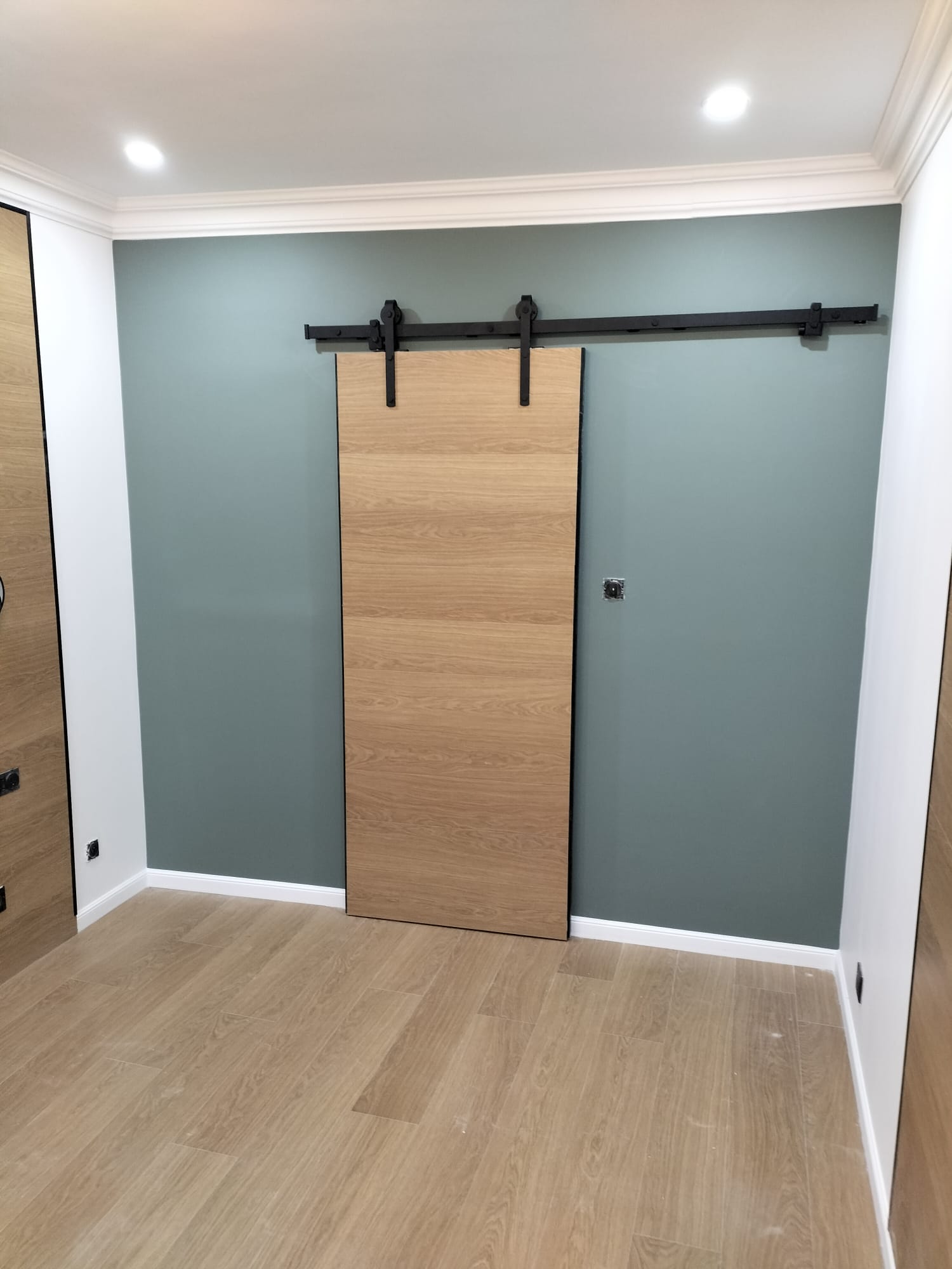 Vue d'une porte coulissante en bois sur un mur peint en vert